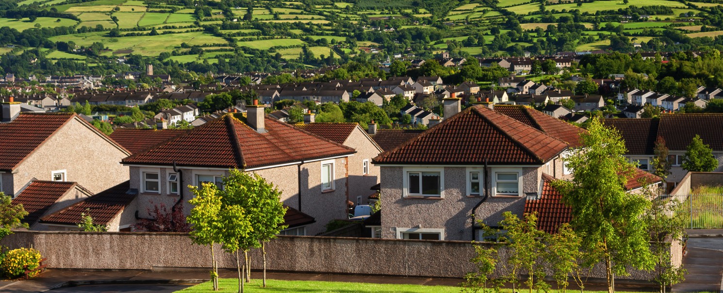 Image of homes with green fields and hills in the background